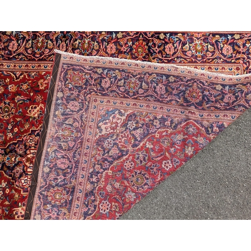 1023 - A 20th century central Persian kashan floor rug carpet. Having a large central medallion on a red gr... 