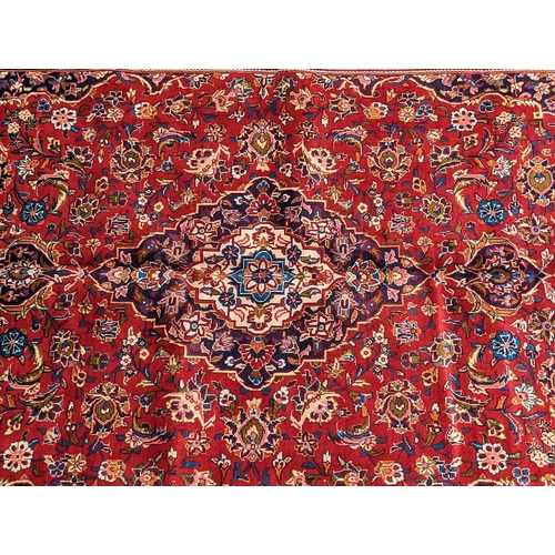 1023 - A 20th century central Persian kashan floor rug carpet. Having a large central medallion on a red gr... 