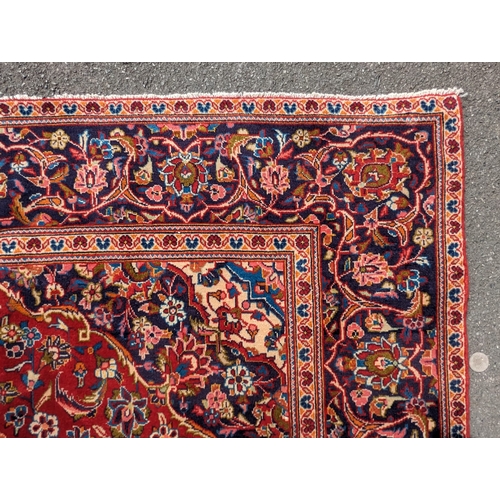1023 - A 20th century central Persian kashan floor rug carpet. Having a large central medallion on a red gr... 