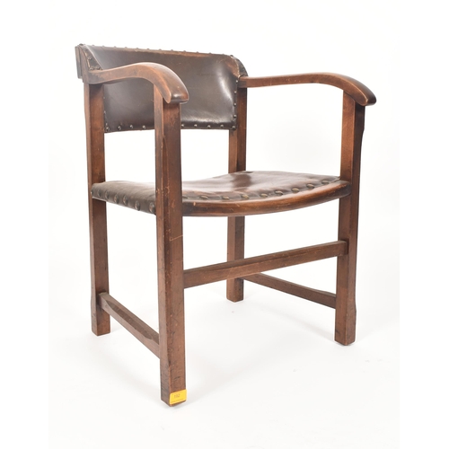 192 - An early 20th century Arts & Crafts oak and leather elbow chair. The chair having a curved leather u... 