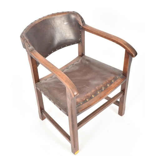 192 - An early 20th century Arts & Crafts oak and leather elbow chair. The chair having a curved leather u... 