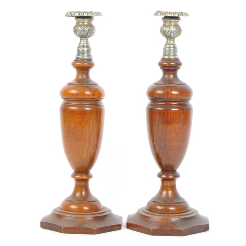247 - A pair of early 20th century turned wood and silver candlesticks. The candlesticks having ornate sil... 