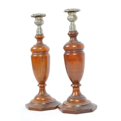 247 - A pair of early 20th century turned wood and silver candlesticks. The candlesticks having ornate sil... 