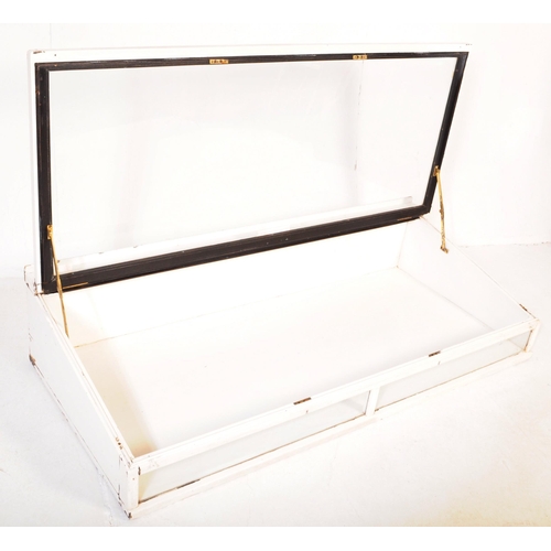 694 - A large 20th century oak glazed haberdashery shop display case having lift up sloped top, all painte... 