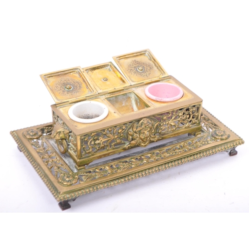 201 - A late Victorian brass inkstand fitted with two round white / pink moulded glass inkwells and incorp... 