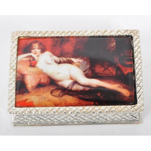 342 - A silver plated pill pot with hinged lid having an enamelled female nude depicted reclining on silks... 