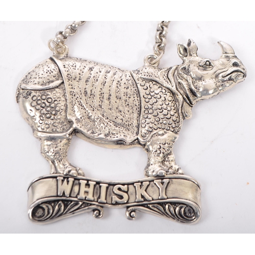 363 - A silver plated whiskey decanter label having a rhinoceros to top over a banner reading Whiskey on c... 