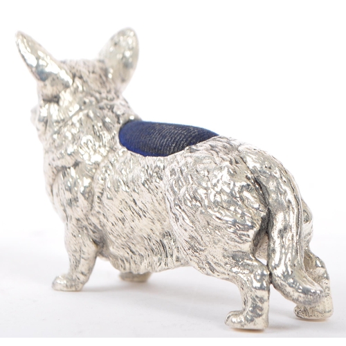 366 - A silver plated pin cushion in the form of a corgi dog having engraved features to body with blue cu... 