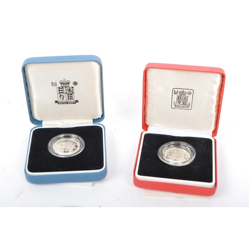 457 - A collection of four coins. To include George V 1935 silver crowns. Royal Mint 1983 United Kingdom s... 