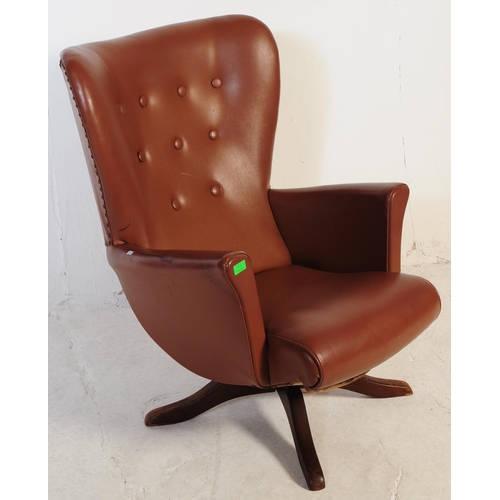 710 - A retro mid 20th century batwing swivel armchair / chair. In the manner of G-Plan being raised on a ... 