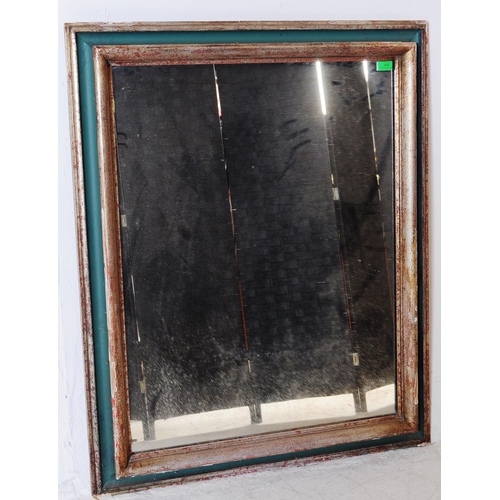 656 - A 20th century silvered and green painted frame mirror. The mirror with cushioned frame having a sil... 