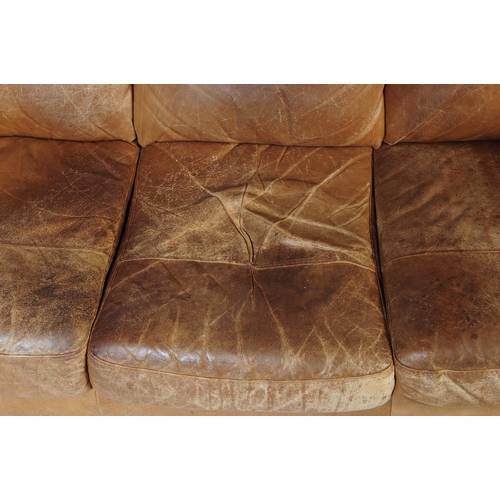 655 - A 20th Century beige / brown leather three seater sofa settee and matching arm chair. Having scrolle... 