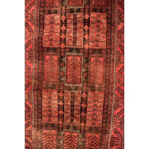 212 - A 20th century Caucasian wool knotted rug. The rug having a series of geometric patterns in red, bur... 