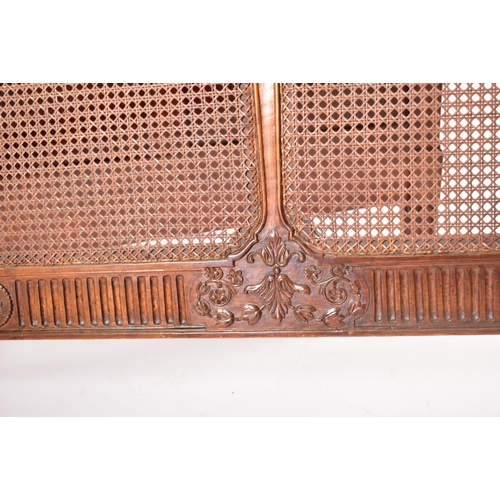 222 - An early 20th century carved walnut & wicker double bed frame. The frame having a hand carved one pi... 