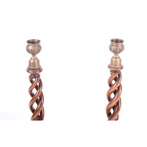 23 - A pair of early 20th century mahogany open barley twist stemmed candlesticks. Each with brass cupped... 