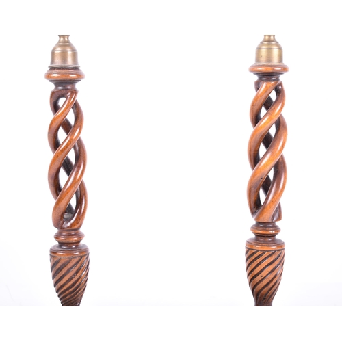 23 - A pair of early 20th century mahogany open barley twist stemmed candlesticks. Each with brass cupped... 