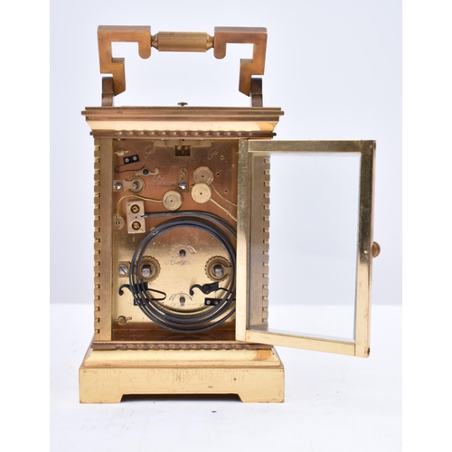 56 - A 20th century brass repeating carriage clock. The desk clock with brass edges & handle and bevelled... 