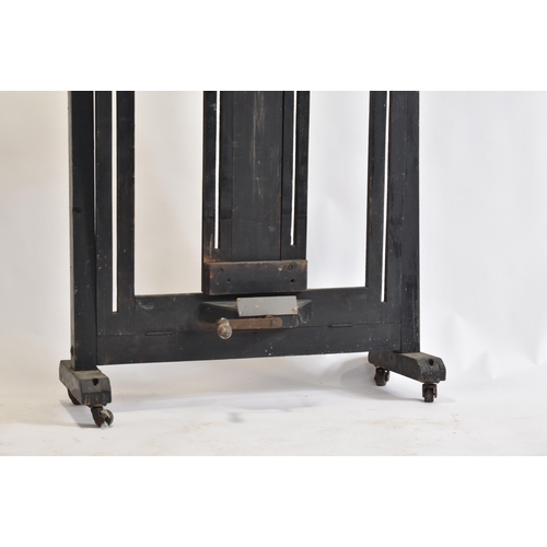 99 - A large Victorian 19th century black painted wood studio artist's easel. The easel raised on brass c... 