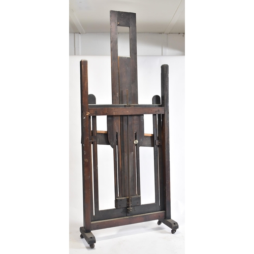 99 - A large Victorian 19th century black painted wood studio artist's easel. The easel raised on brass c... 