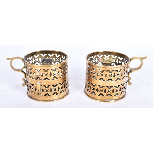 324 - A pair of mid-late 19th century brass candle stick holders / nightlights. Each with finger ring and ... 