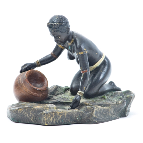 441 - An early 20th century cold painted bronze figure of a kneeling African tribal woman filling a pot wi... 