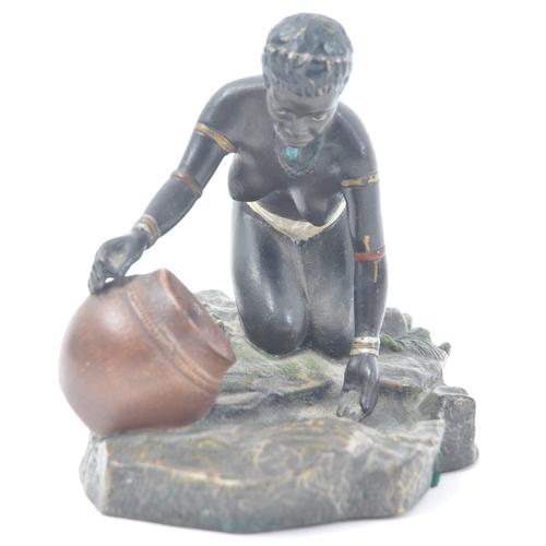 441 - An early 20th century cold painted bronze figure of a kneeling African tribal woman filling a pot wi... 