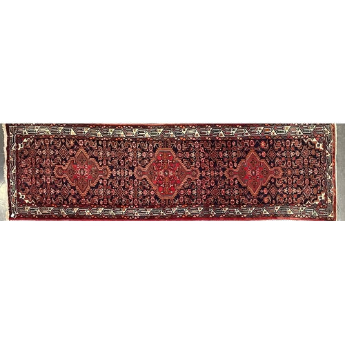 274 - A 20th century Persian Islamic Belouch floor carpet runner rug. The rug having a series of three geo... 