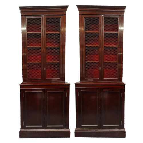 398 - A pair of tall early 20th century Victorian style mahogany bookcase cabinets. Each having a pediment... 