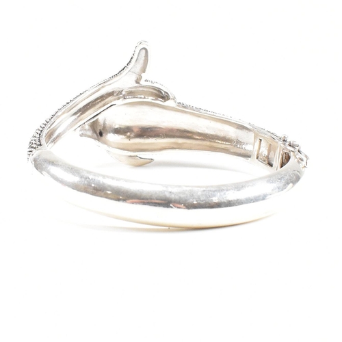 133 - A contemporary white metal and marcasite novelty dolphin bangle having ruby set eyes. Weight approx ... 