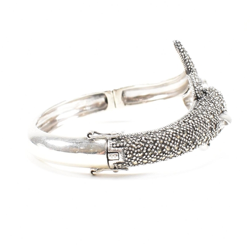 133 - A contemporary white metal and marcasite novelty dolphin bangle having ruby set eyes. Weight approx ... 