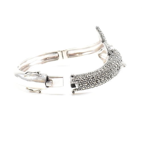 133 - A contemporary white metal and marcasite novelty dolphin bangle having ruby set eyes. Weight approx ... 