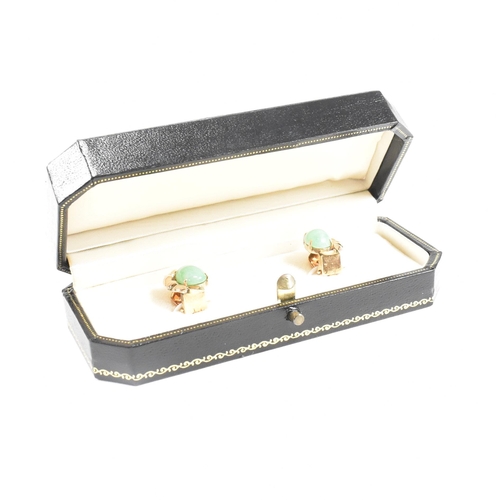 135 - A pair of mid century gold and jade ear clip earrings. The earrings set with jade cabochons. Unmarke... 