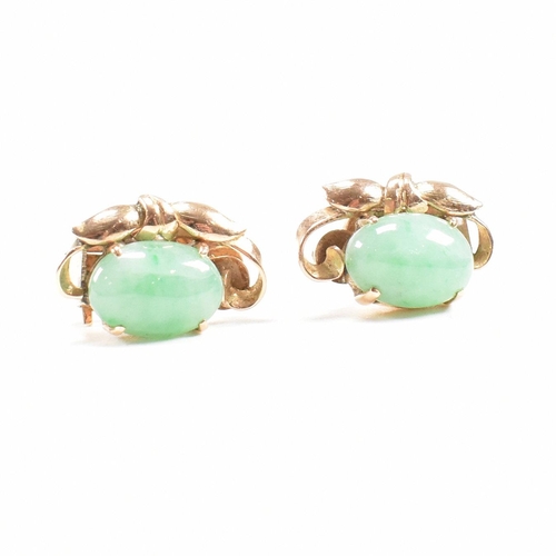 135 - A pair of mid century gold and jade ear clip earrings. The earrings set with jade cabochons. Unmarke... 