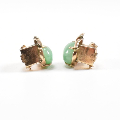 135 - A pair of mid century gold and jade ear clip earrings. The earrings set with jade cabochons. Unmarke... 