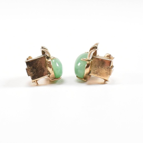 135 - A pair of mid century gold and jade ear clip earrings. The earrings set with jade cabochons. Unmarke... 