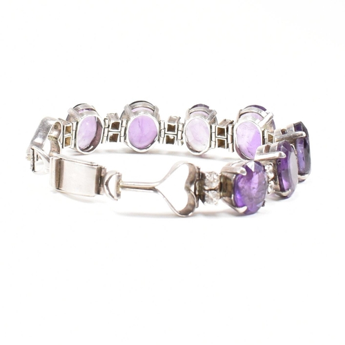 173 - An silver and amethyst bracelet . The bracelet having graduated oval cut amethyst with white topaz a... 