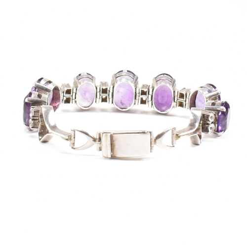 173 - An silver and amethyst bracelet . The bracelet having graduated oval cut amethyst with white topaz a... 