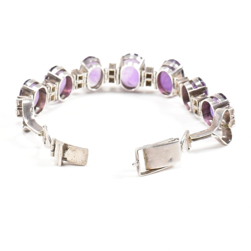 173 - An silver and amethyst bracelet . The bracelet having graduated oval cut amethyst with white topaz a... 