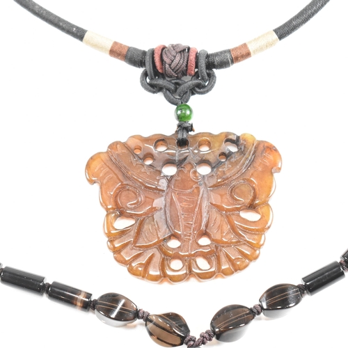 206 - Two carved Chinese hardstone necklaces. A necklace strung with a carved brown jade moth surmounted b... 