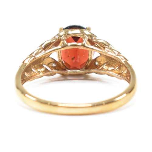 296 - A hallmarked 9ct gold and garnet ring. The ring set with an oval cut garnet to diamond set pierced f... 