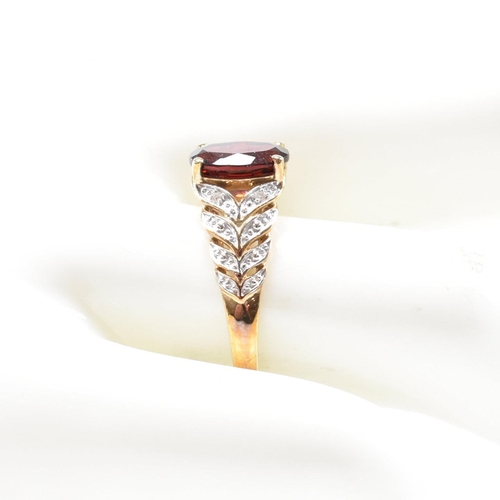 296 - A hallmarked 9ct gold and garnet ring. The ring set with an oval cut garnet to diamond set pierced f... 