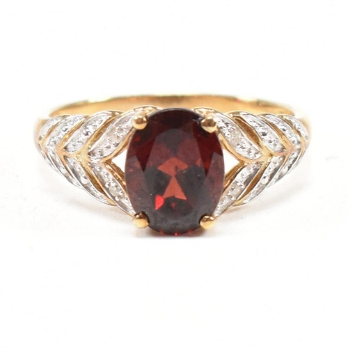 296 - A hallmarked 9ct gold and garnet ring. The ring set with an oval cut garnet to diamond set pierced f... 