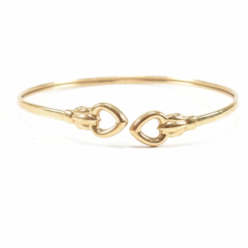 337 - A gold torque bangle. The bangle having heart finials with tube band. Marked 375. tests indicate 9ct... 