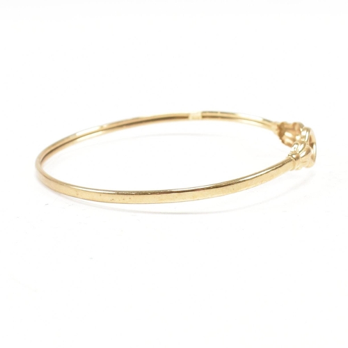 337 - A gold torque bangle. The bangle having heart finials with tube band. Marked 375. tests indicate 9ct... 