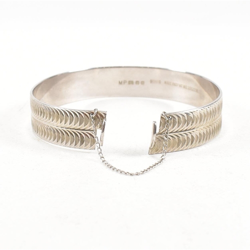 391 - Two hallmarked 925 silver hinged bangles. The bangles to include etched foliate decorated bangle, ha... 