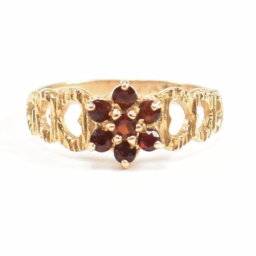 450 - A hallmarked 9ct gold and garnet cluster ring having textured pierced heart shoulders. Weight 2g. Si... 