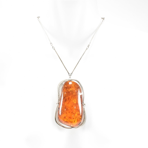 454 - A white metal and amber pendant necklace together with an amber and resin set hinged bangle and a gr... 