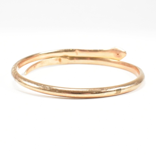 8 - A hallmarked 9ct gold snake bangle. The bangle in the form of a coiled snake. Hallmarked Birmingham.... 