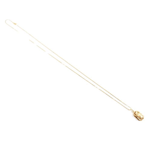 87 - An 18ct gold Scarab pendant necklace. The fine box chain strung with a scarab beetle pendant. The ch... 