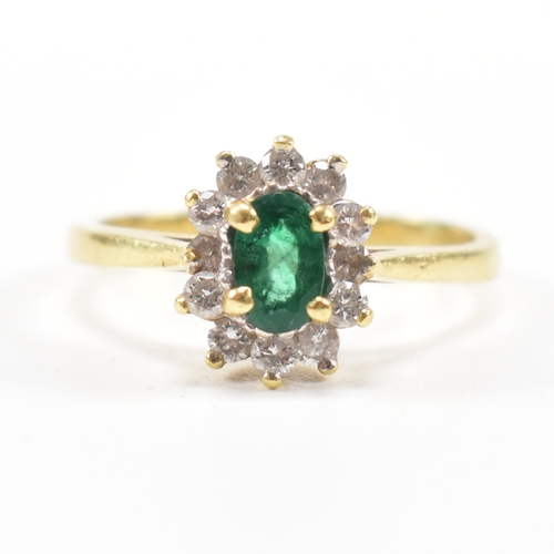 460 - An 18ct gold emerald and diamond cluster ring.  The ring set with a central oval cut emerald framed ... 